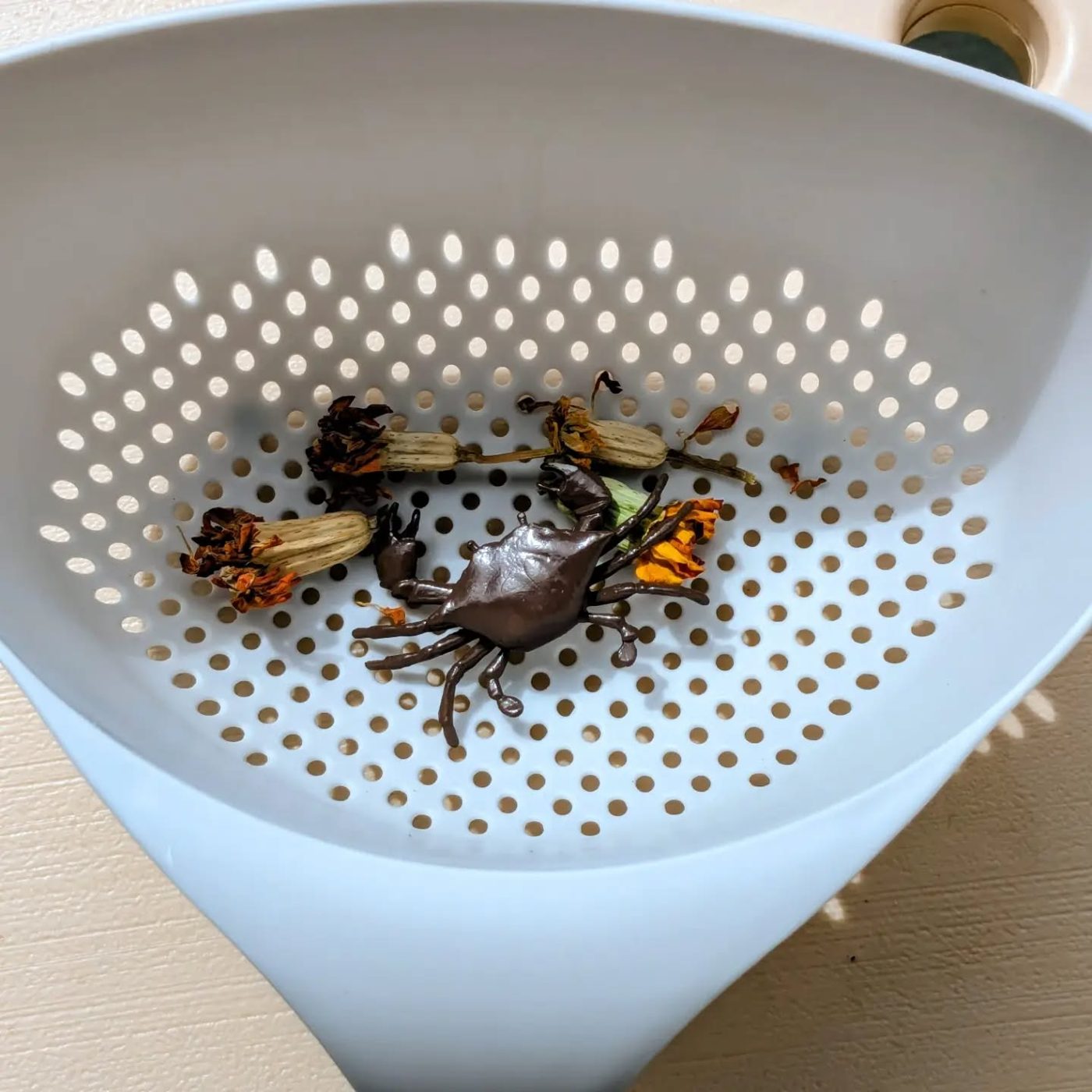 A toy crab with dried marigolds in a sorting basket